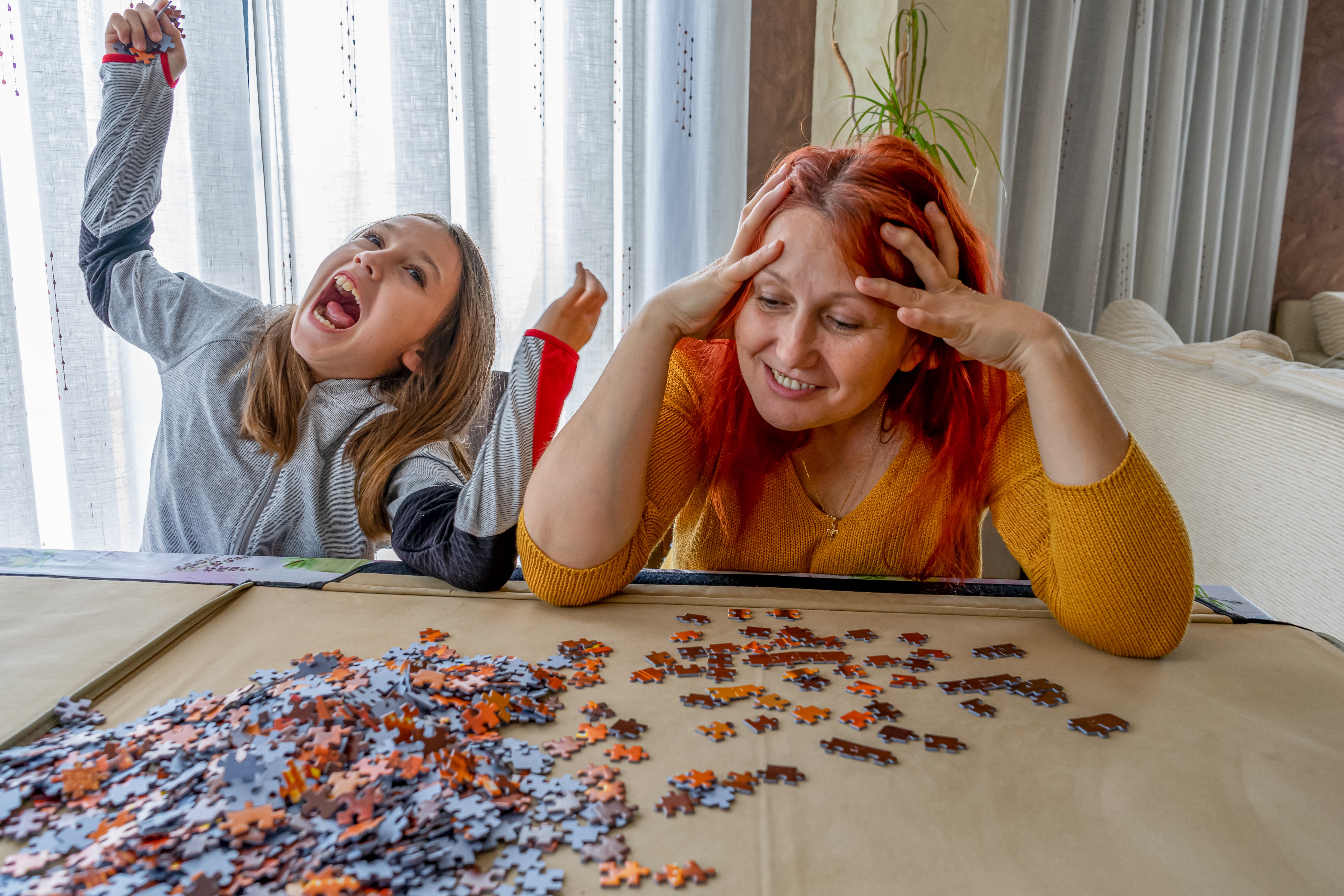 An adult and young person doing a jigsaw together and smiling