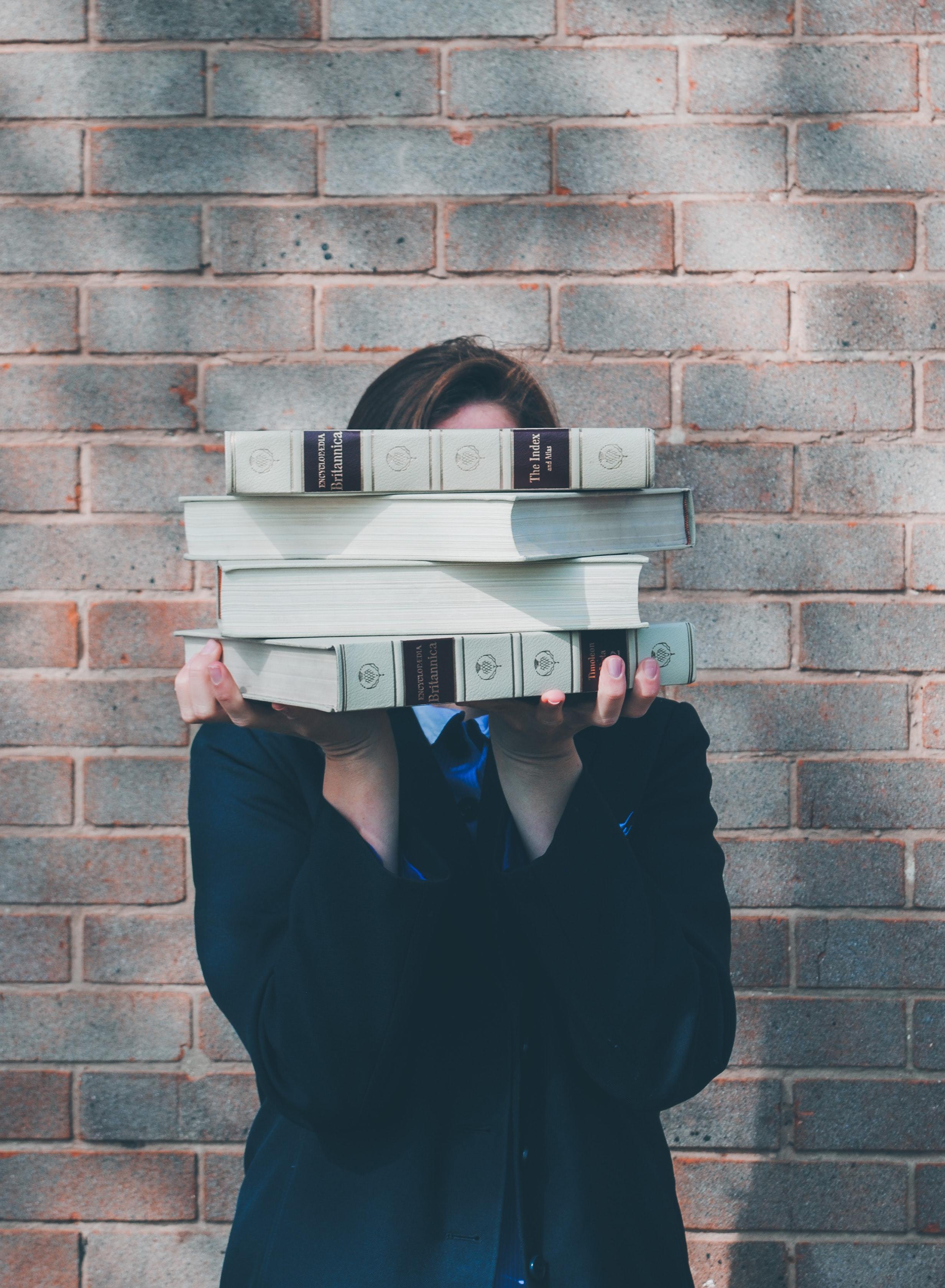 Lady holding a pile of books infront of her face