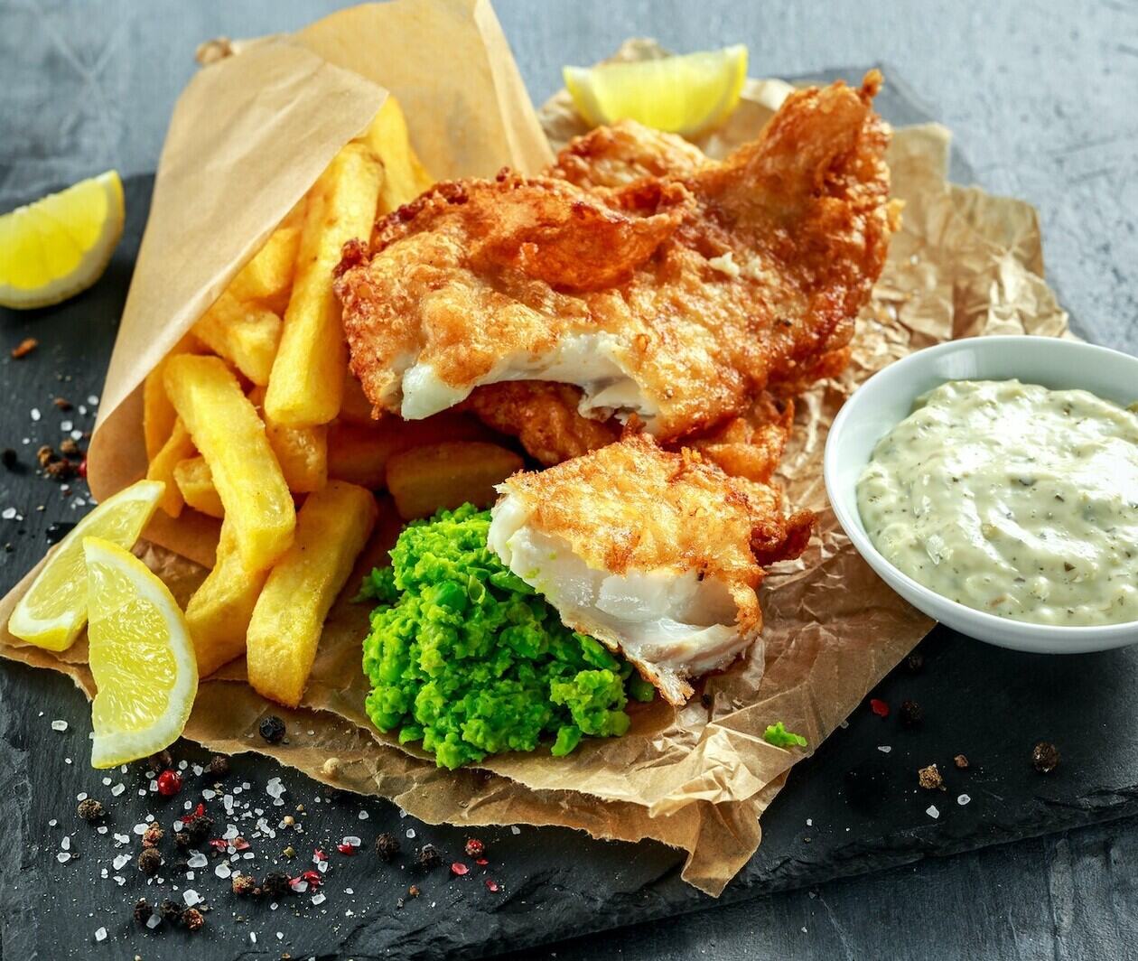 A serving of fish and chips, with peas