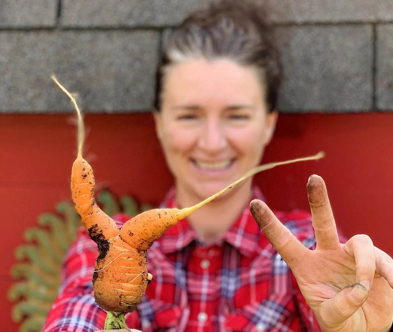 A woman holds a misshapen carrot