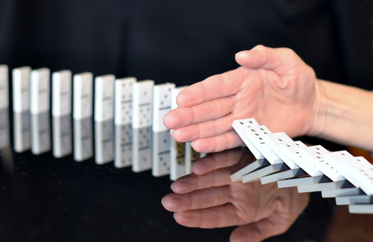 Hand stopping dominoes falling