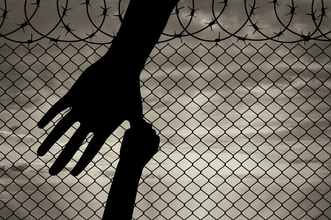 A big hand coming from the top encounters a smaller hand in the background, barbed wire appearing from the bottom.