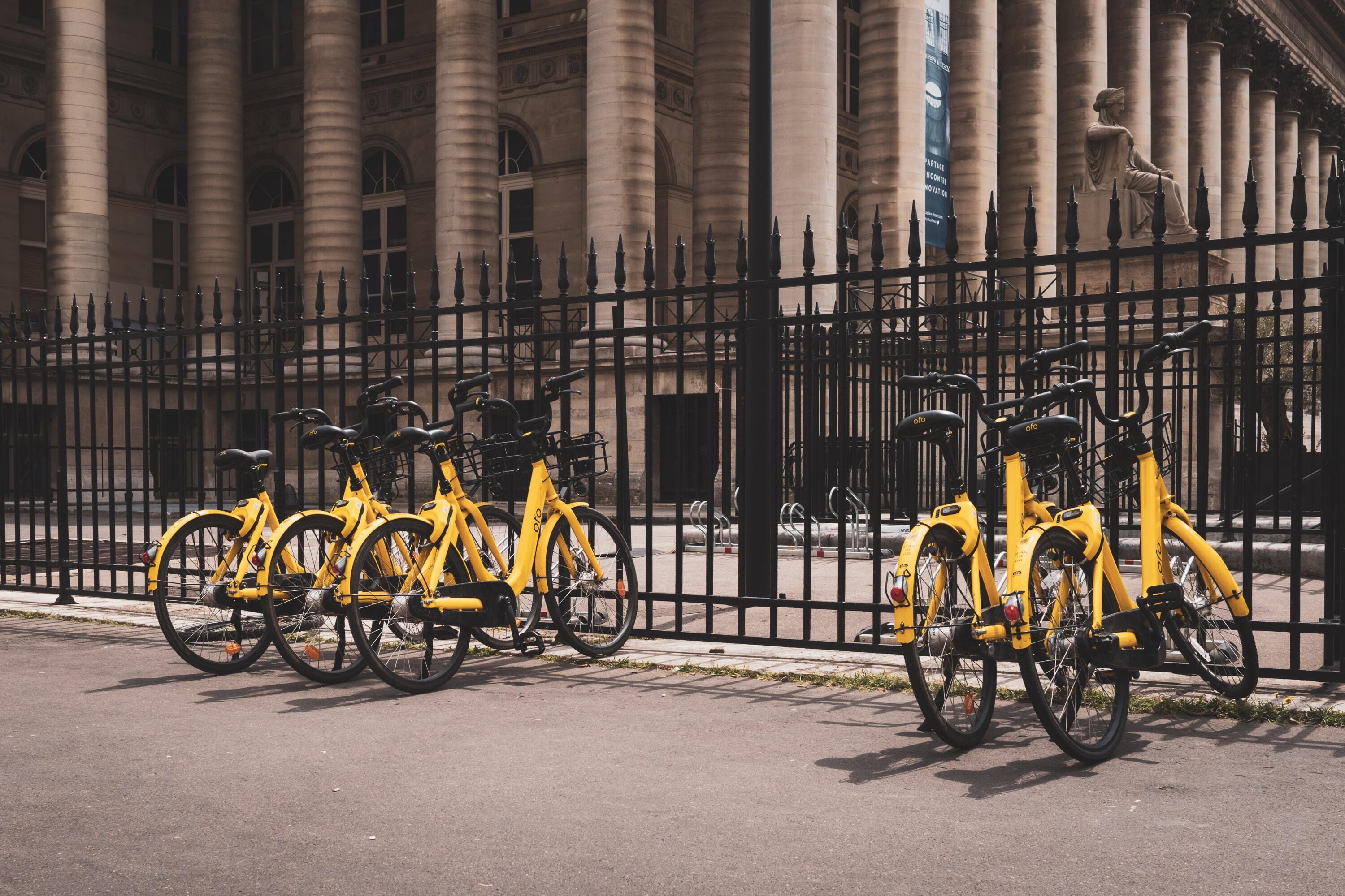 Yellow for-hire bicycles next to black fence