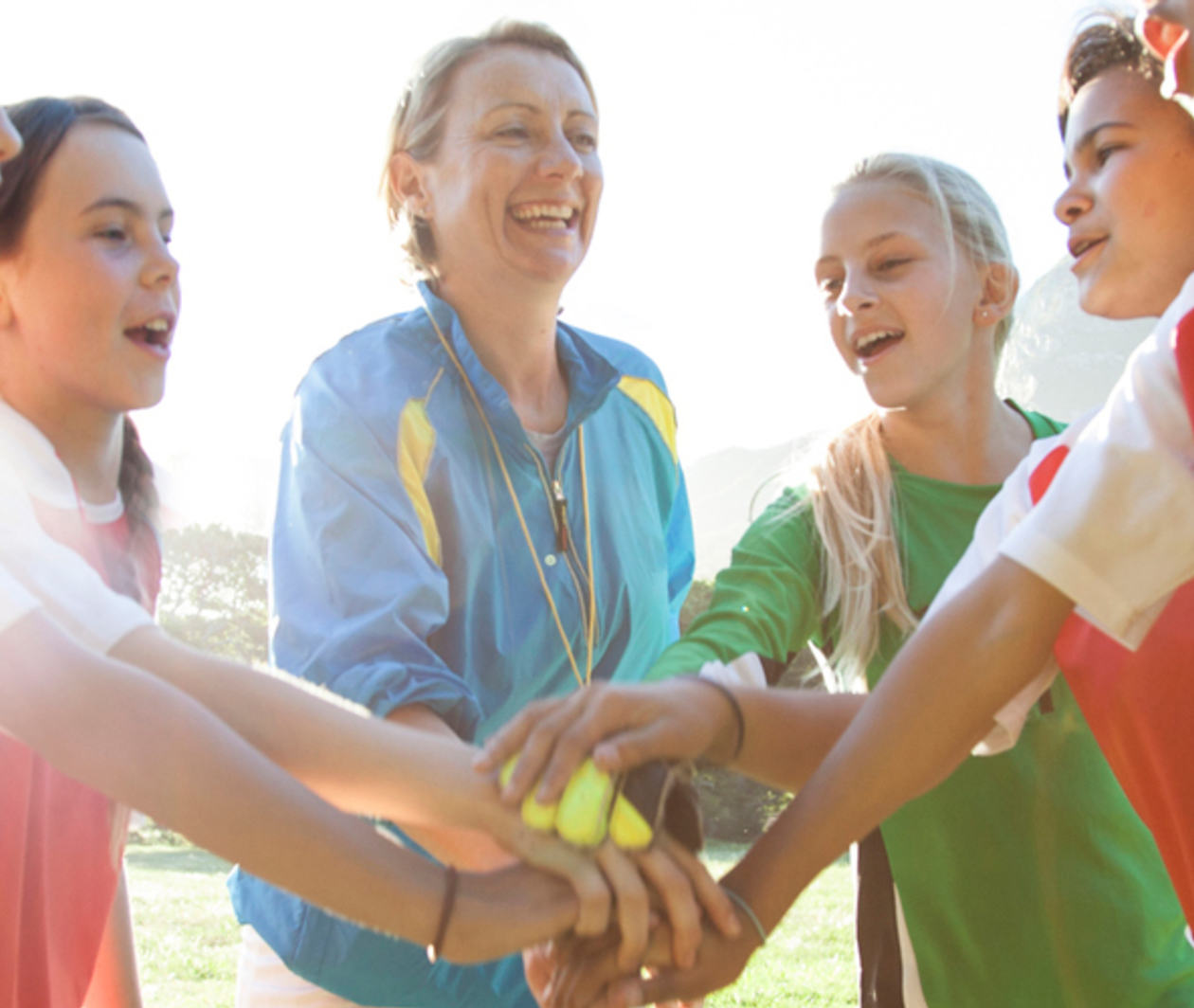 Girls soccer team with their coach in a huddle