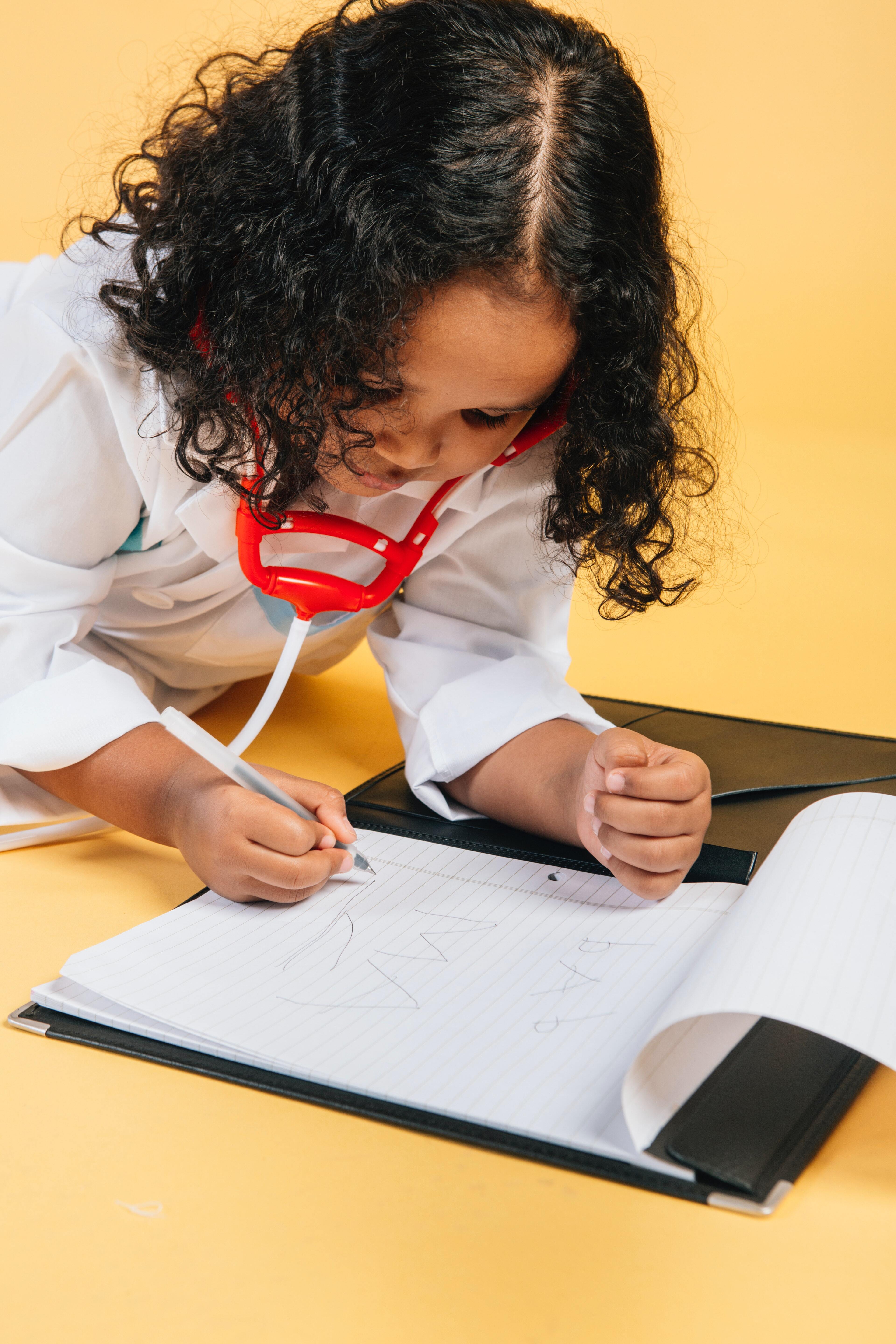 Little girl role playing as a doctor and writing on notepad