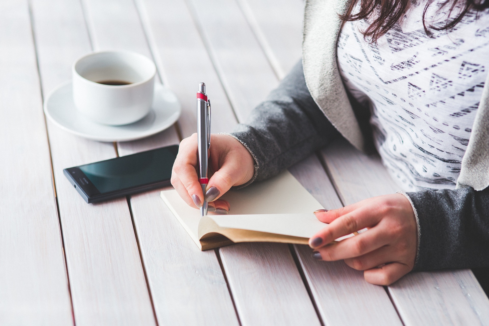 A close up of someone's hand writing in a notebook