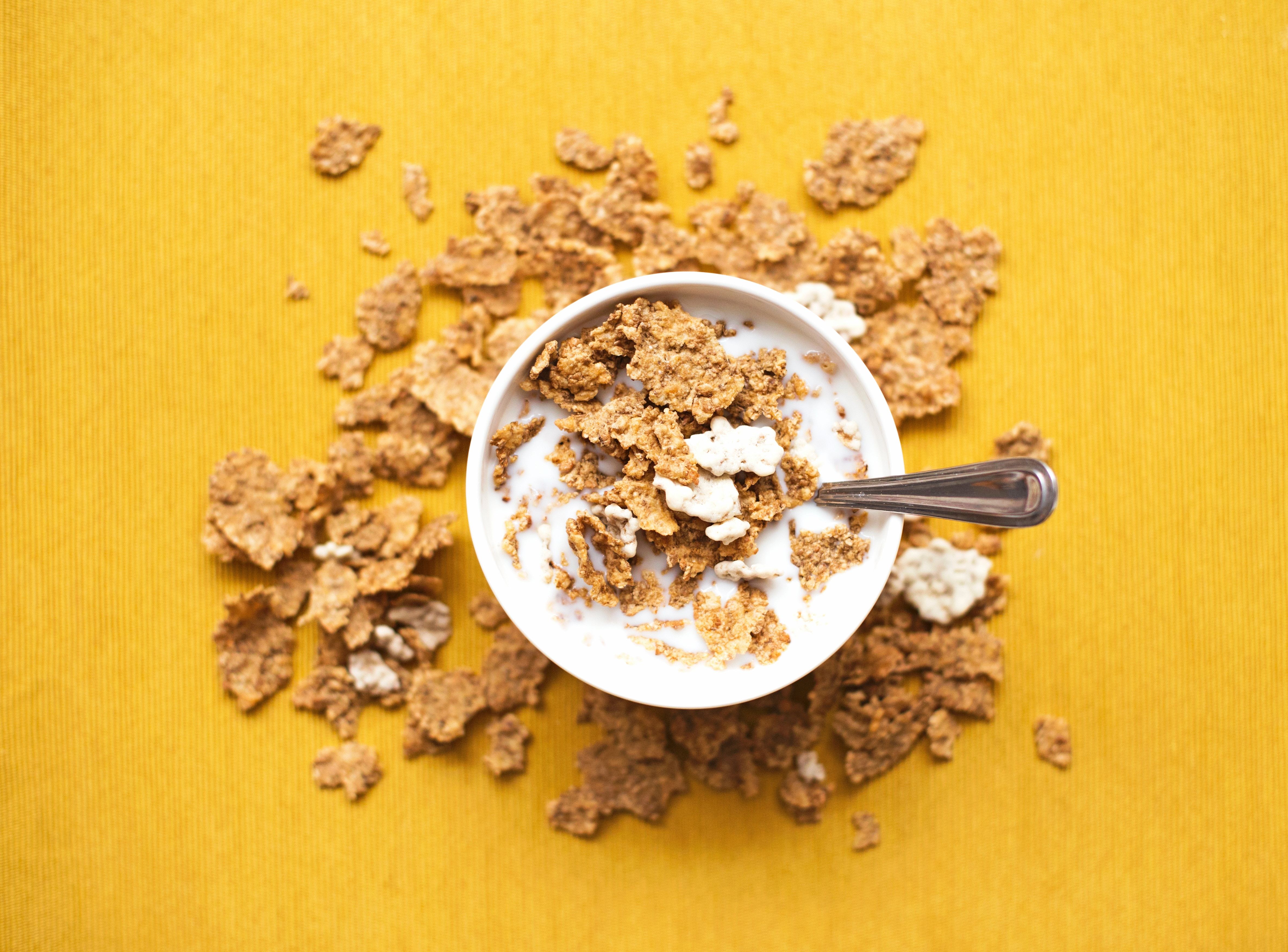 A bowl of breakfast cereal with some cereal scattered around it