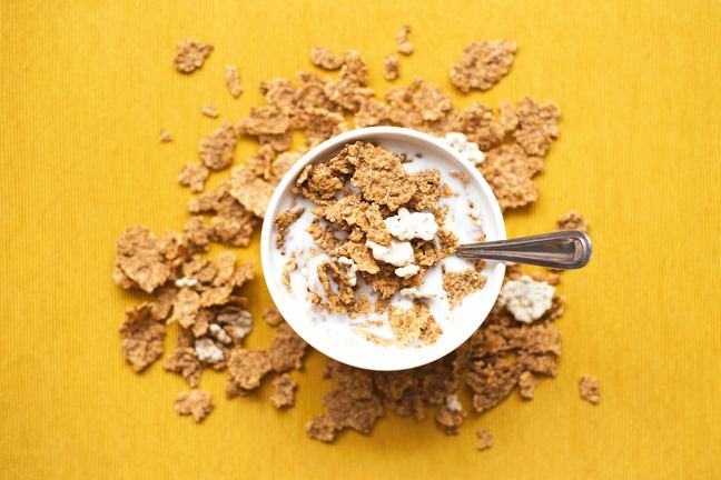 A bowl of breakfast cereal with some cereal scattered around it