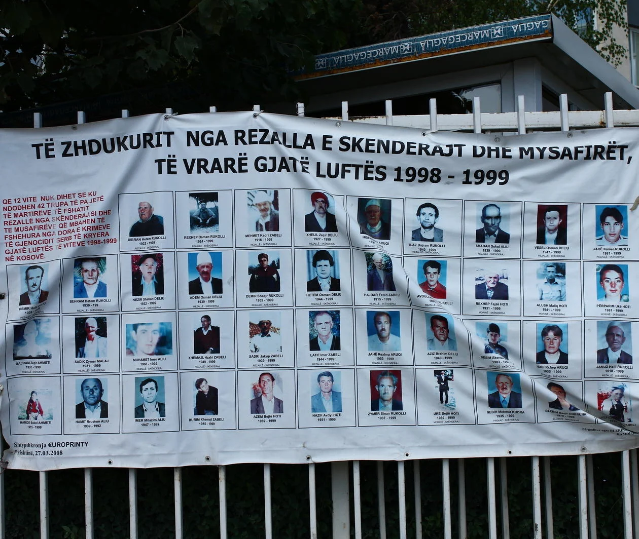 A banner affixed to a fence and displaying photographs of people missing and presumed dead as a result of the war in Kosovo 1998-99