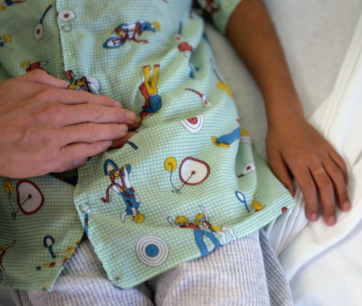Paediatrician examining a baby sitting on mother's lap during a checkup.