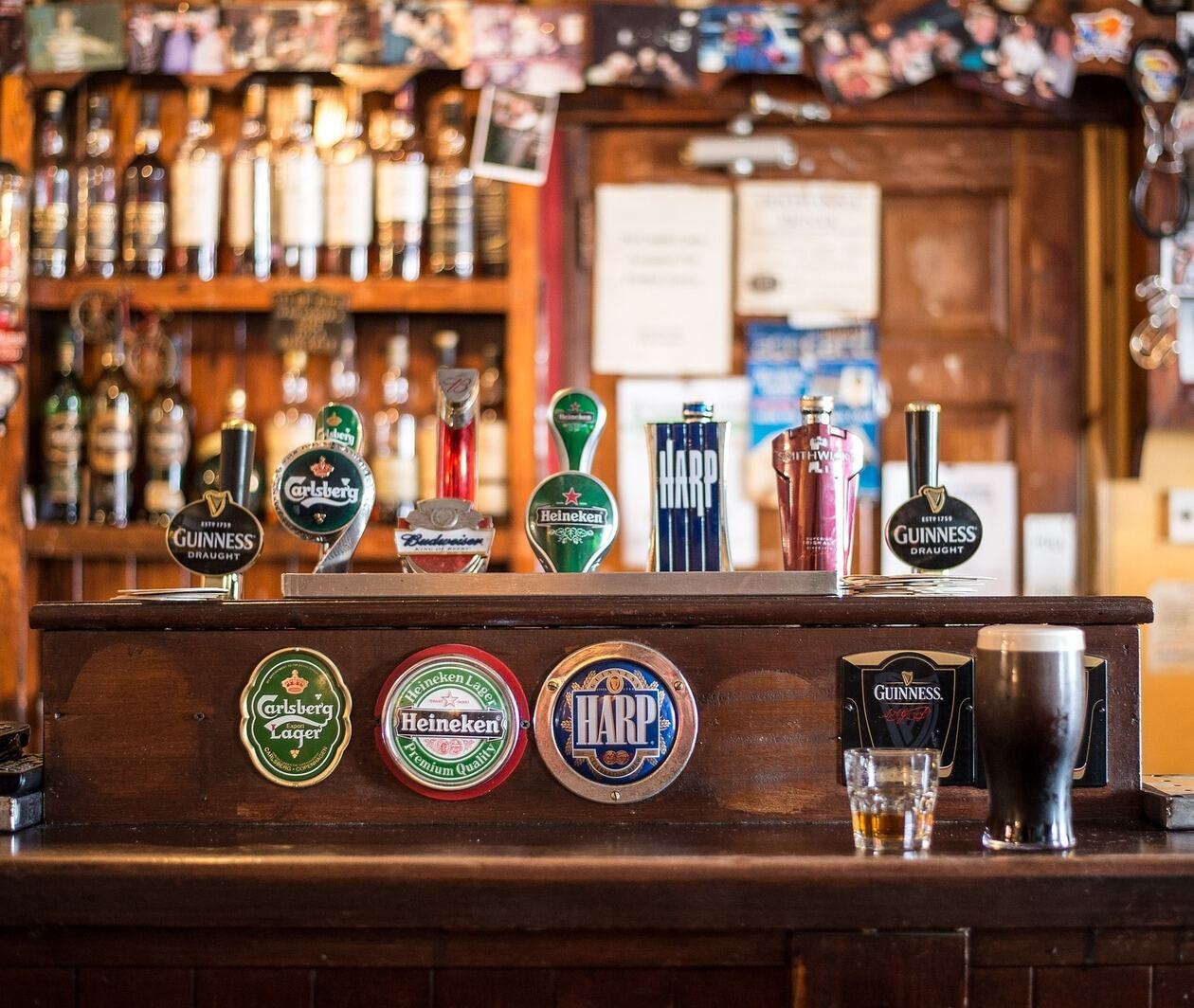 A typical bar in a UK pub, stocked with various ales on tap and bottles stacked in rows behind.