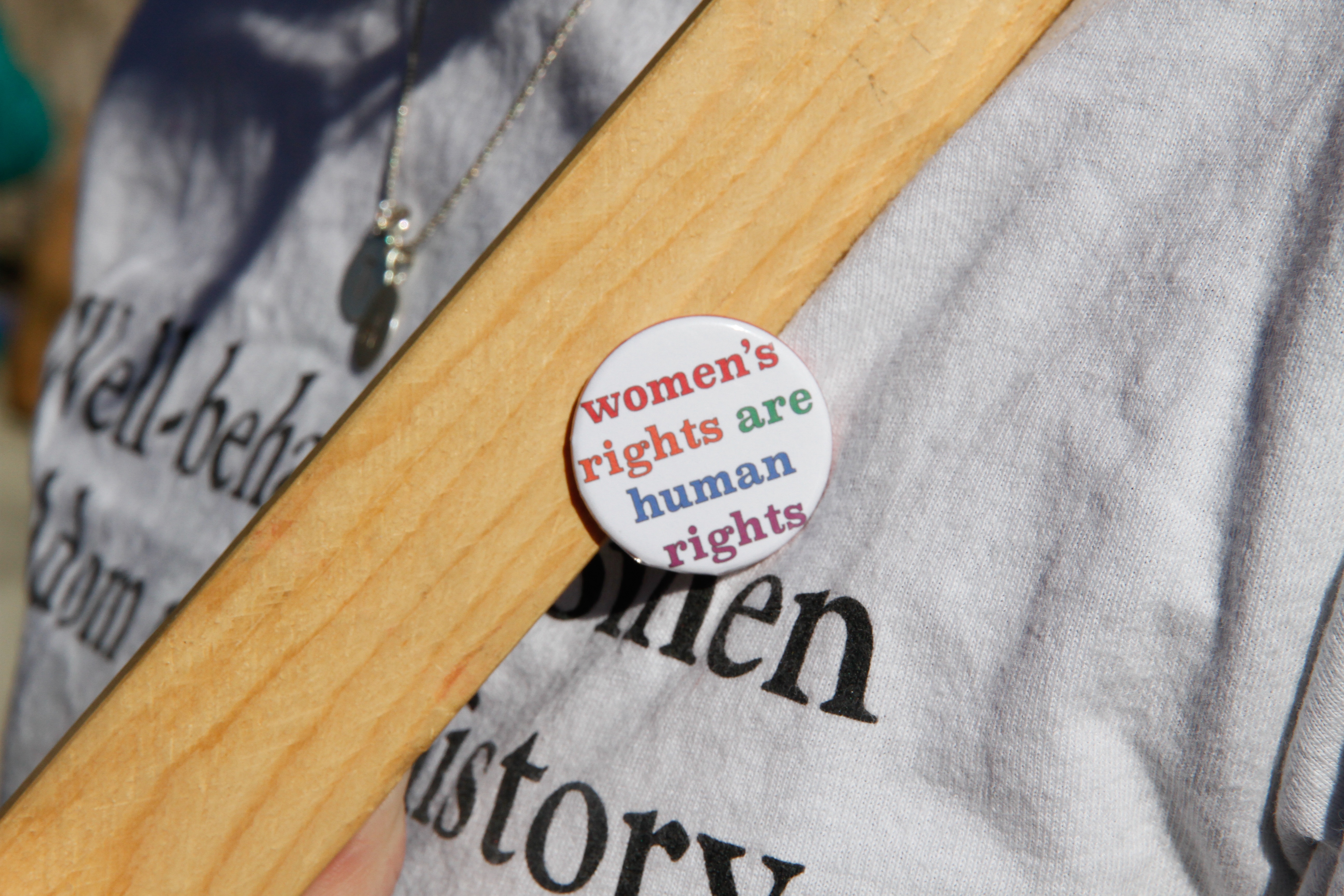 A closeup of a woman's torso, wearing a badge with the slogan 'women's rights are human rights'.