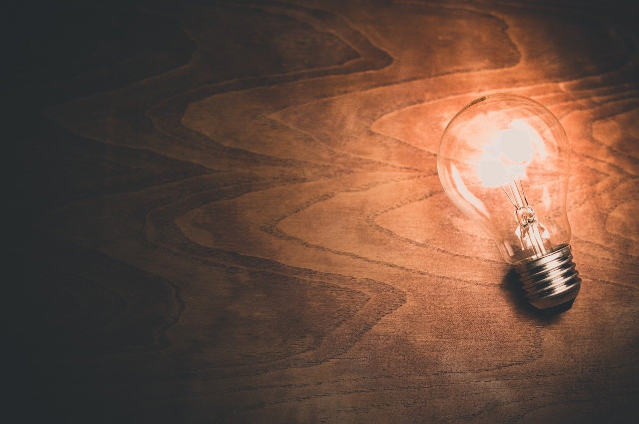 A lightbulb glows on a beautifully smooth wooden desktop