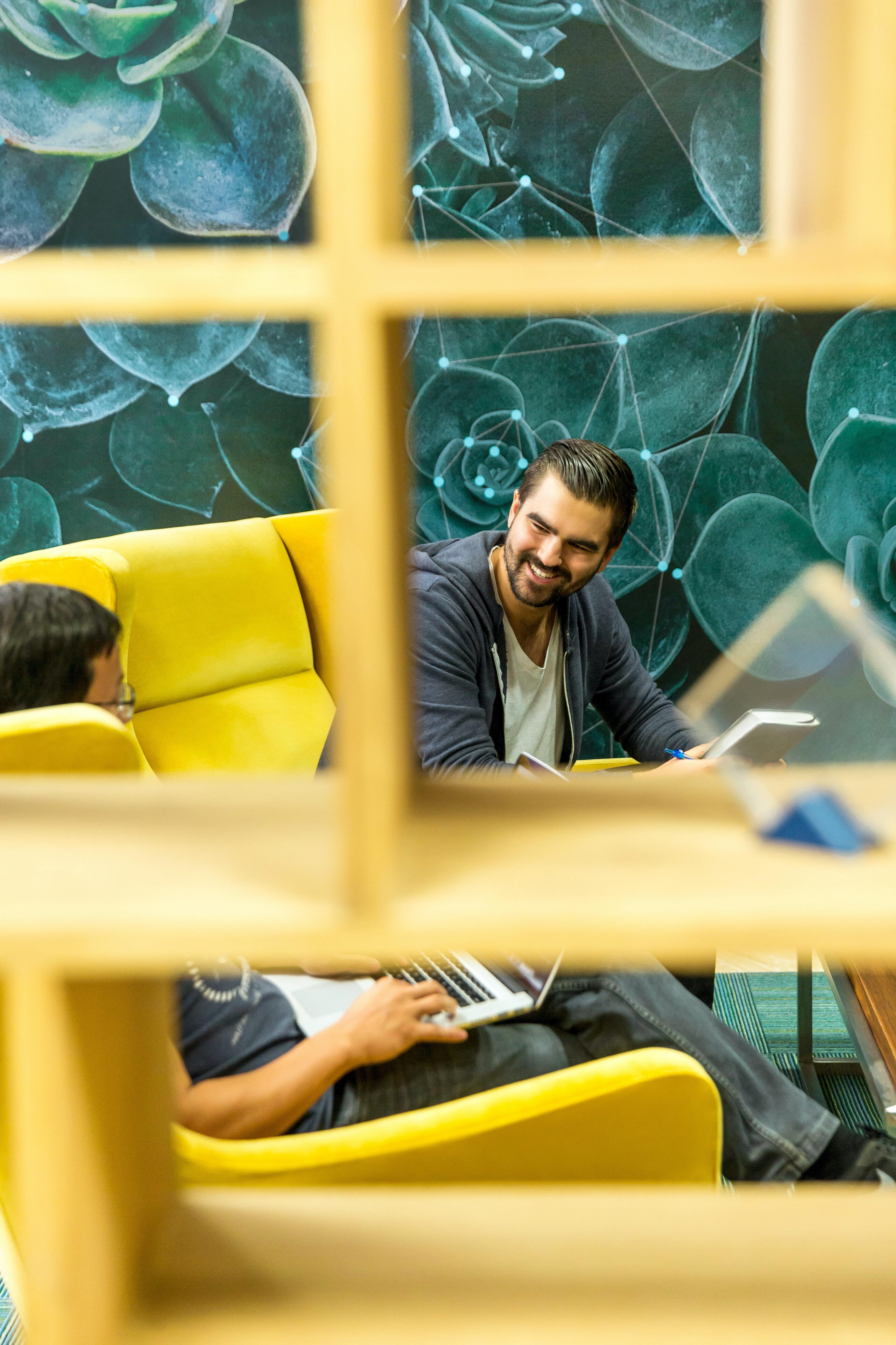 Man smiling, viewed through a yellow window frame