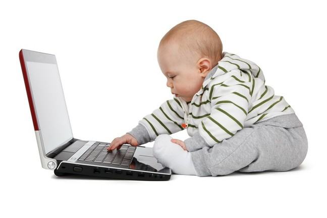 A baby playing on a laptop