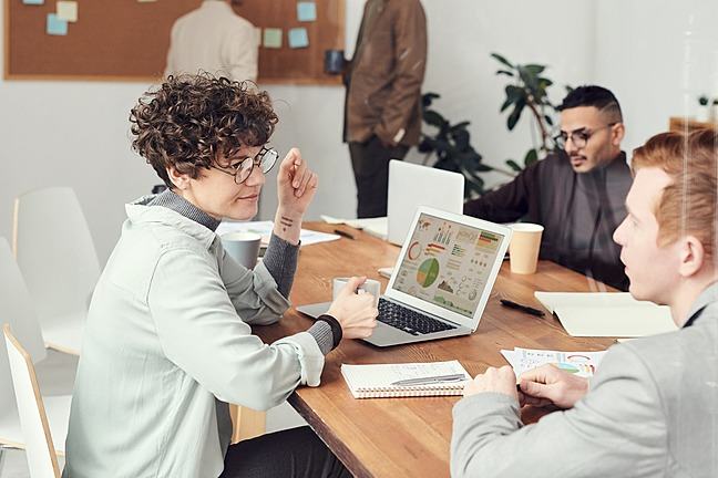 woman with graphs on laptop listening to colleague