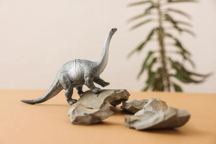 A dinosaur model walking on a rock