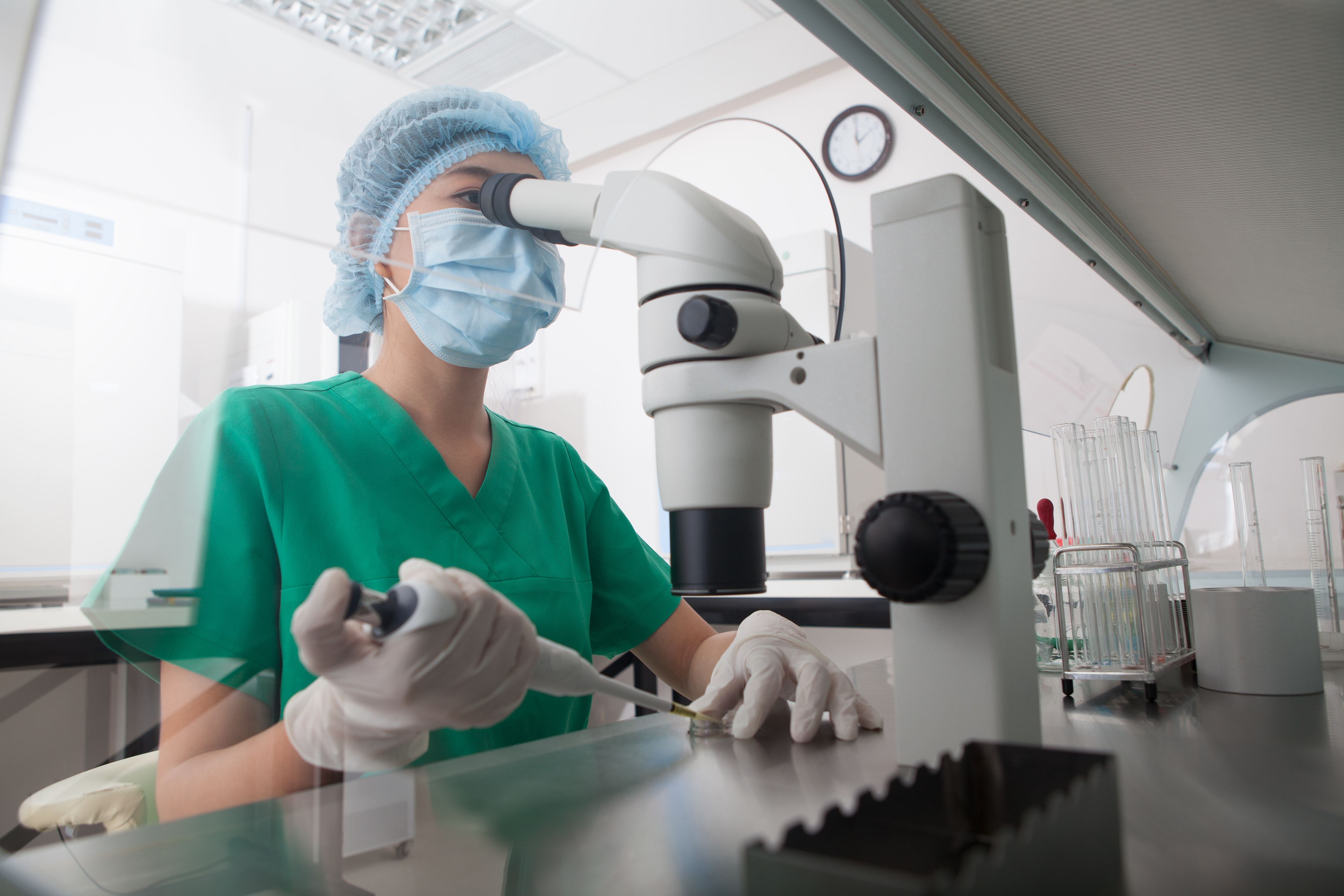 A woman looking through a microscope in a laboratory.