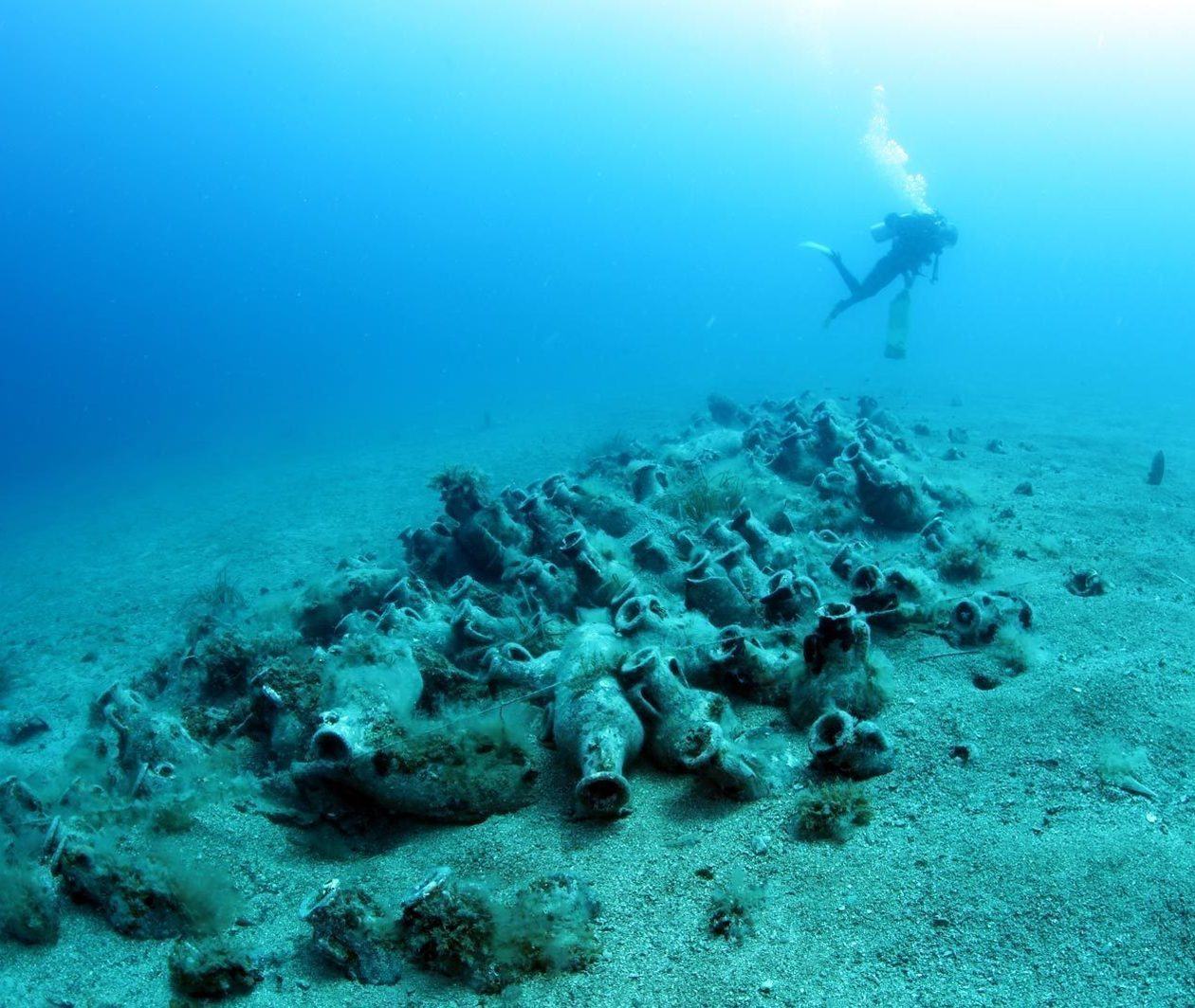 A diver exploring some amphora from a shipwreck