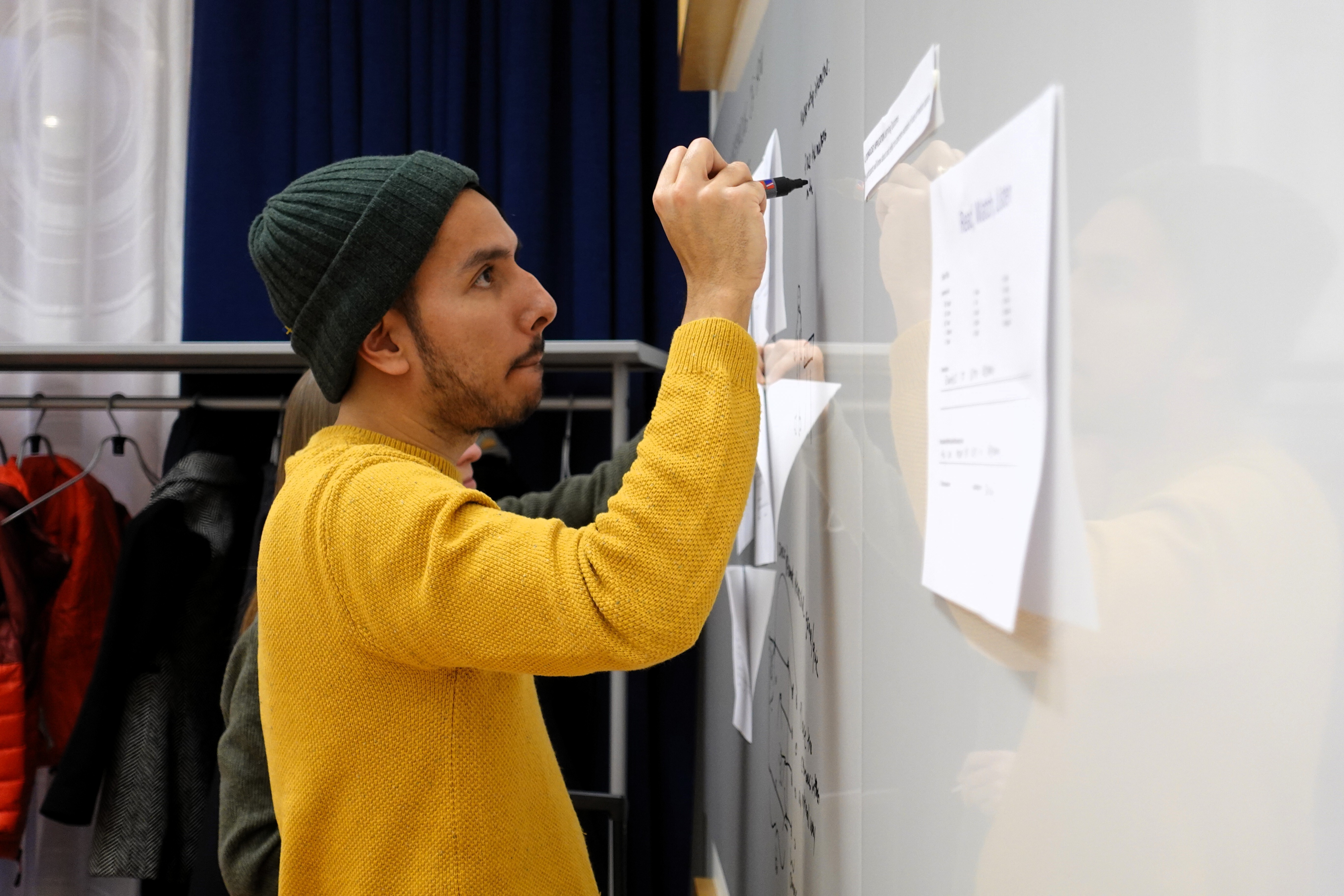 A man is writing on a whiteboard.