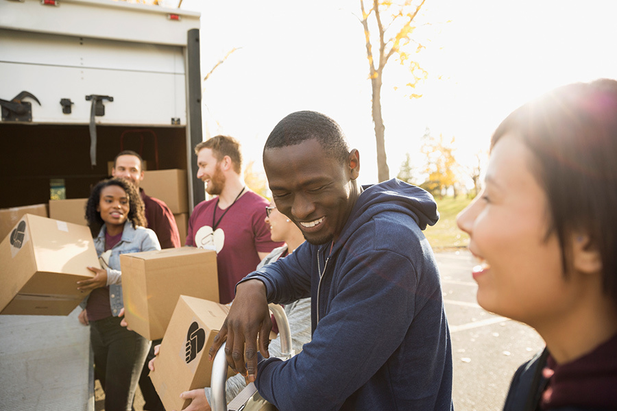 Smiling volunteers unloading cardboard boxes from truck