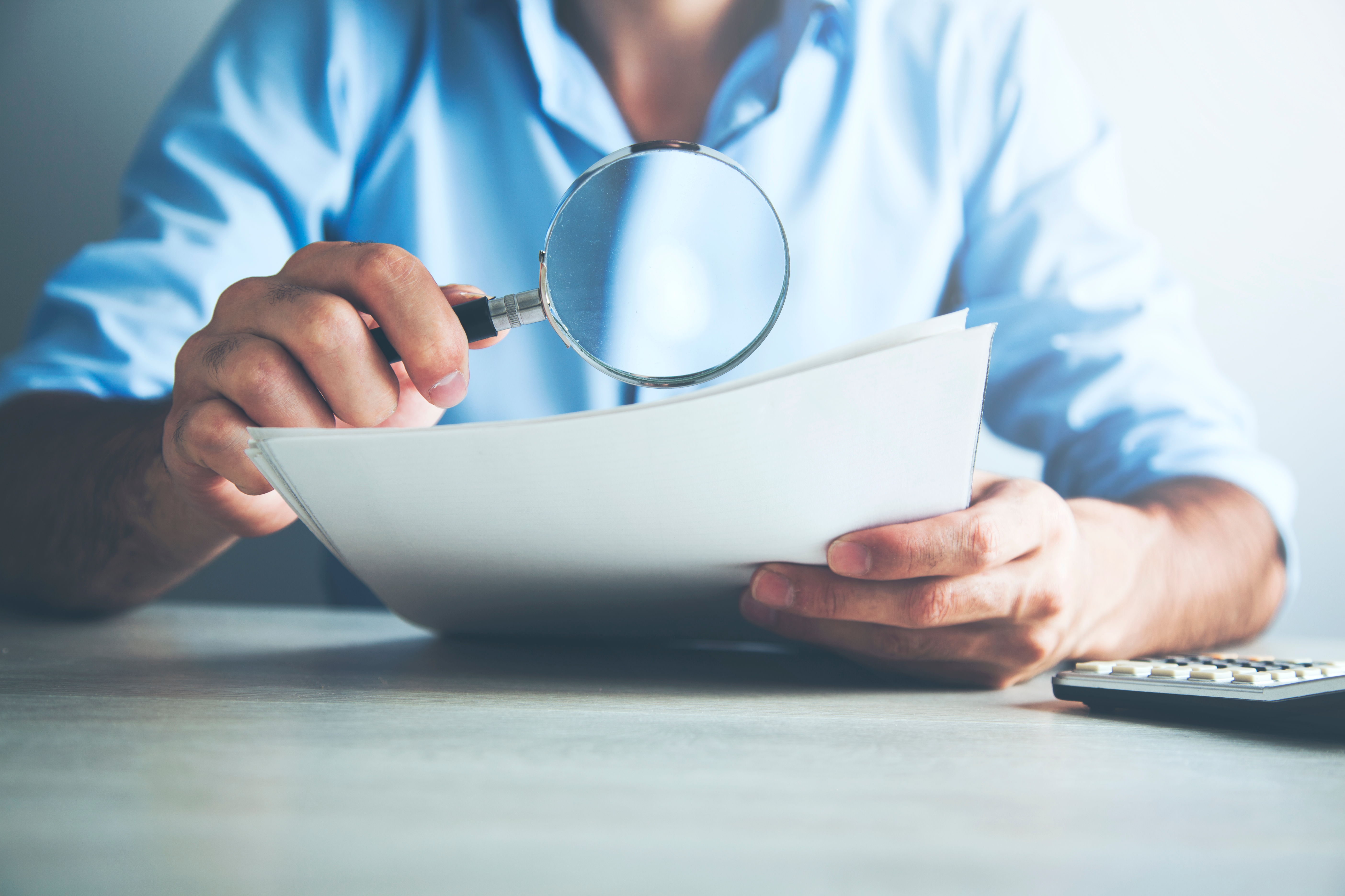 Businessman looking through a magnifying glass to documents