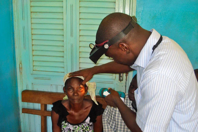 An eye care worker examines a female patient's eyes.