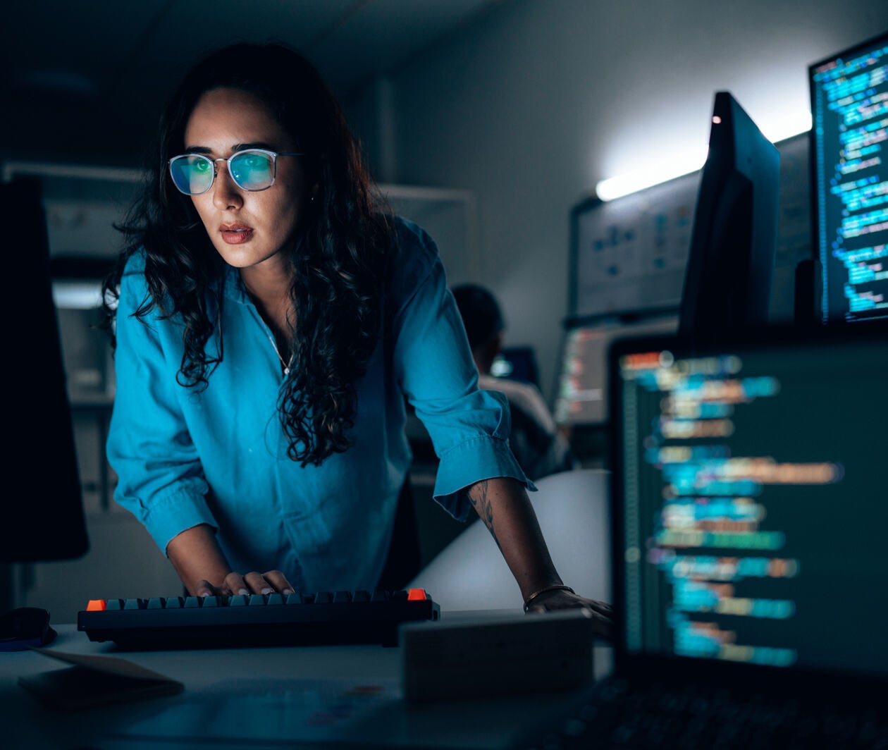 Hispanic Female software developer coding at night in office 