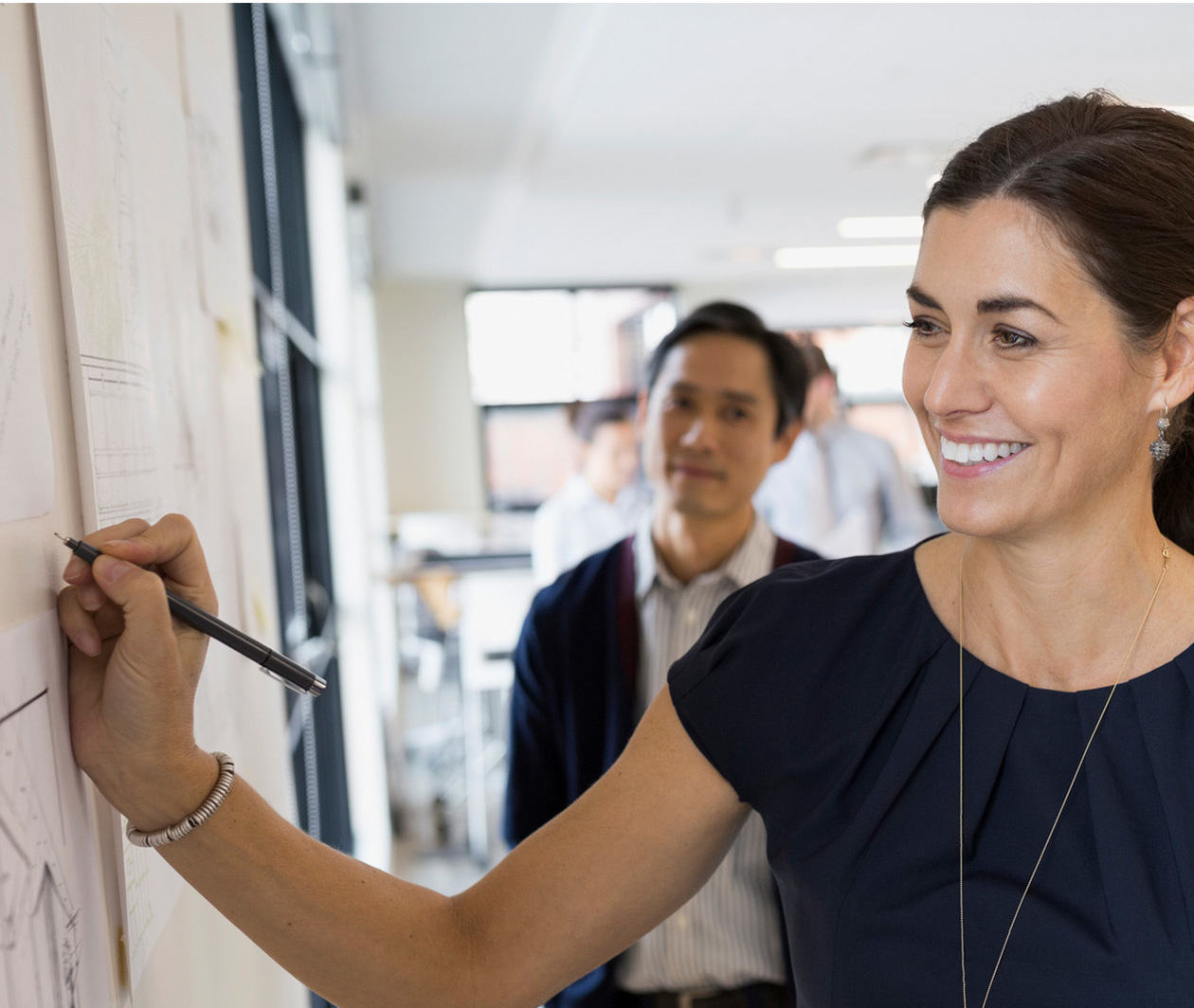 Smiling businesswoman writing on a wall.