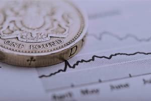 A coin sits on top of a line graph on a piece of paper – a metaphor for financial planning.