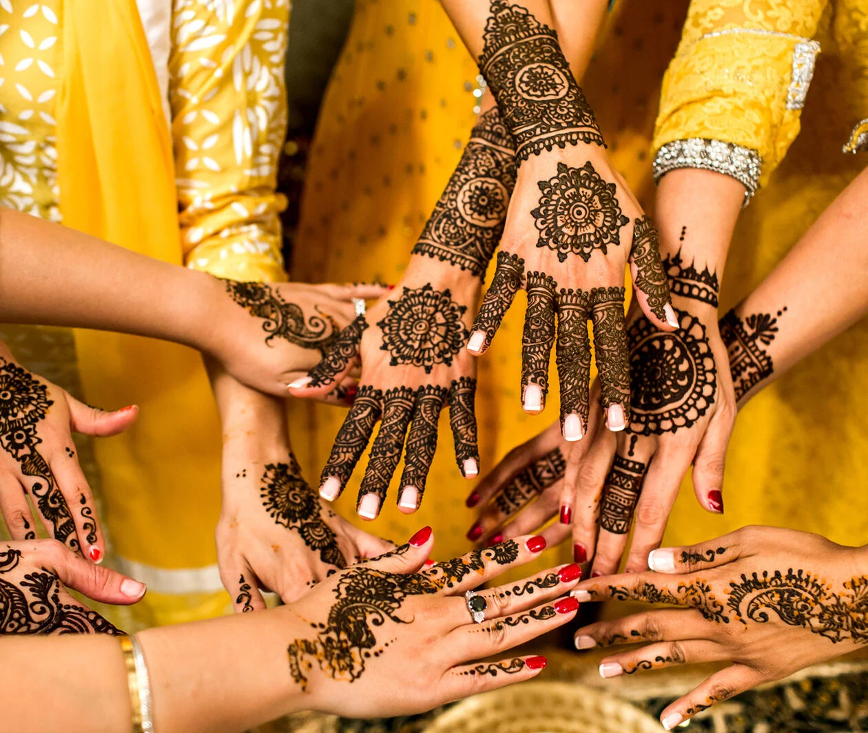 A number of hands all placed together in a circle displaying their Henna body art