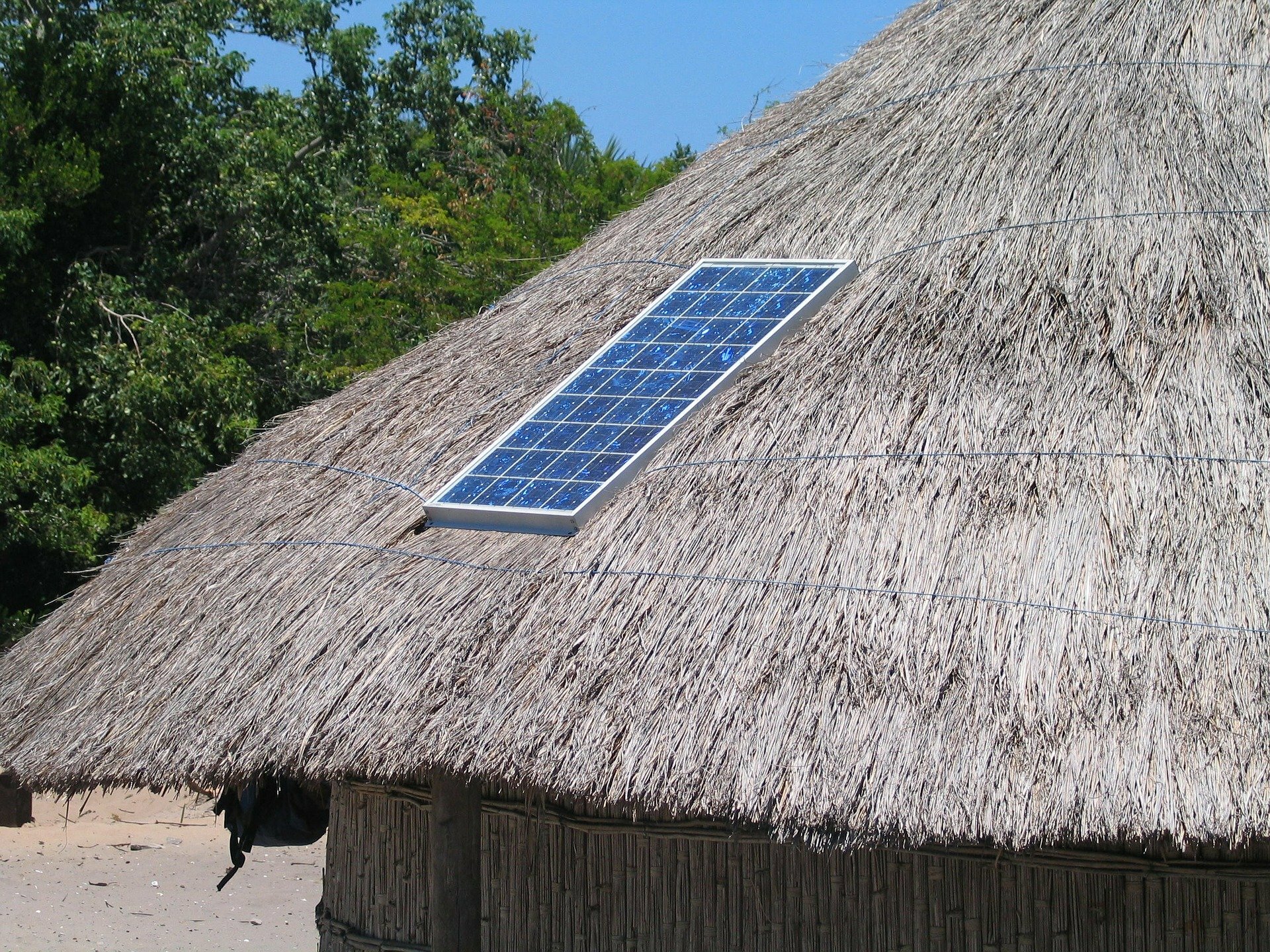 Photo of a solar panel on a straw roof hut