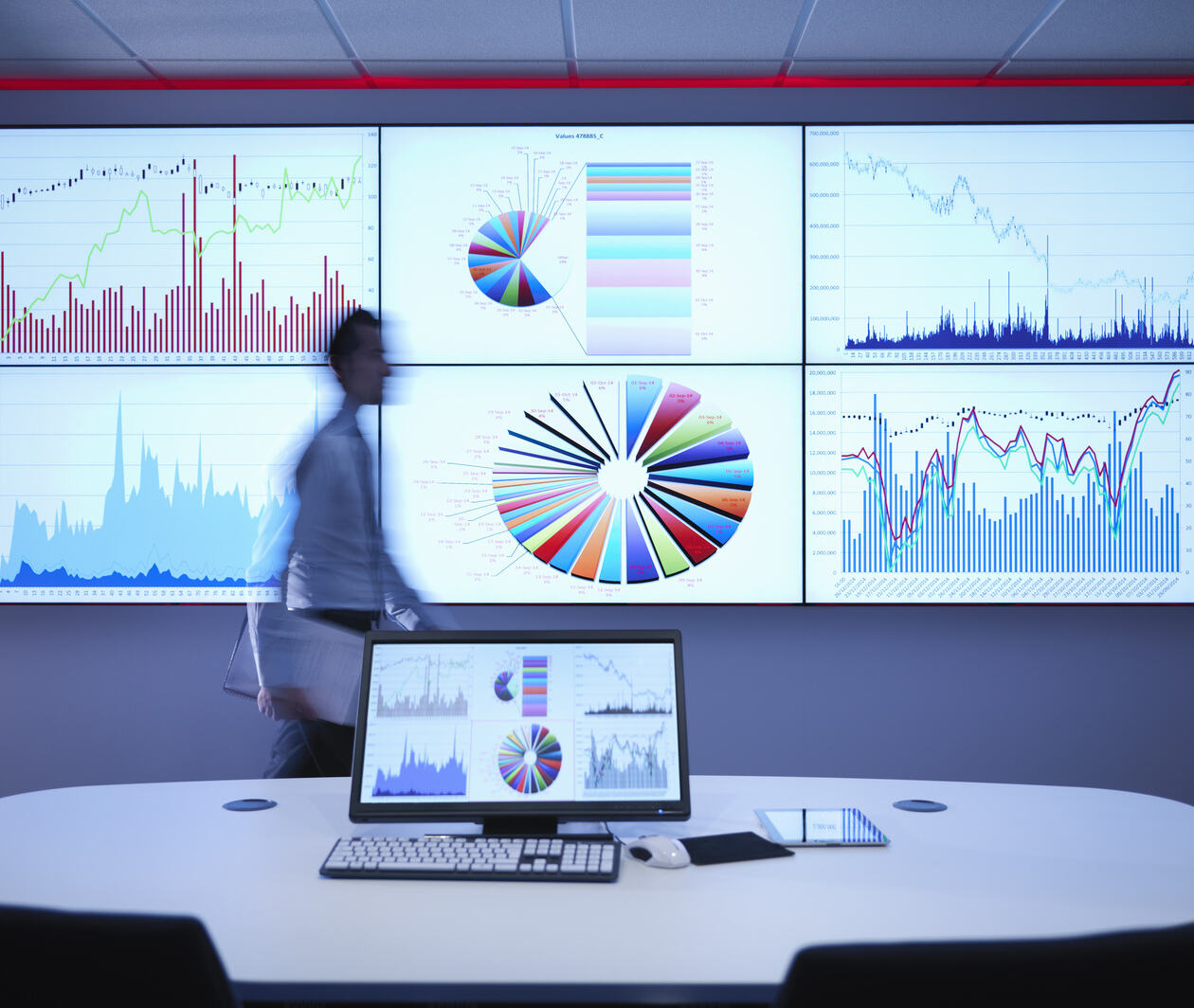 Businessman walking in front of graphs on screen showing forecasting of business.