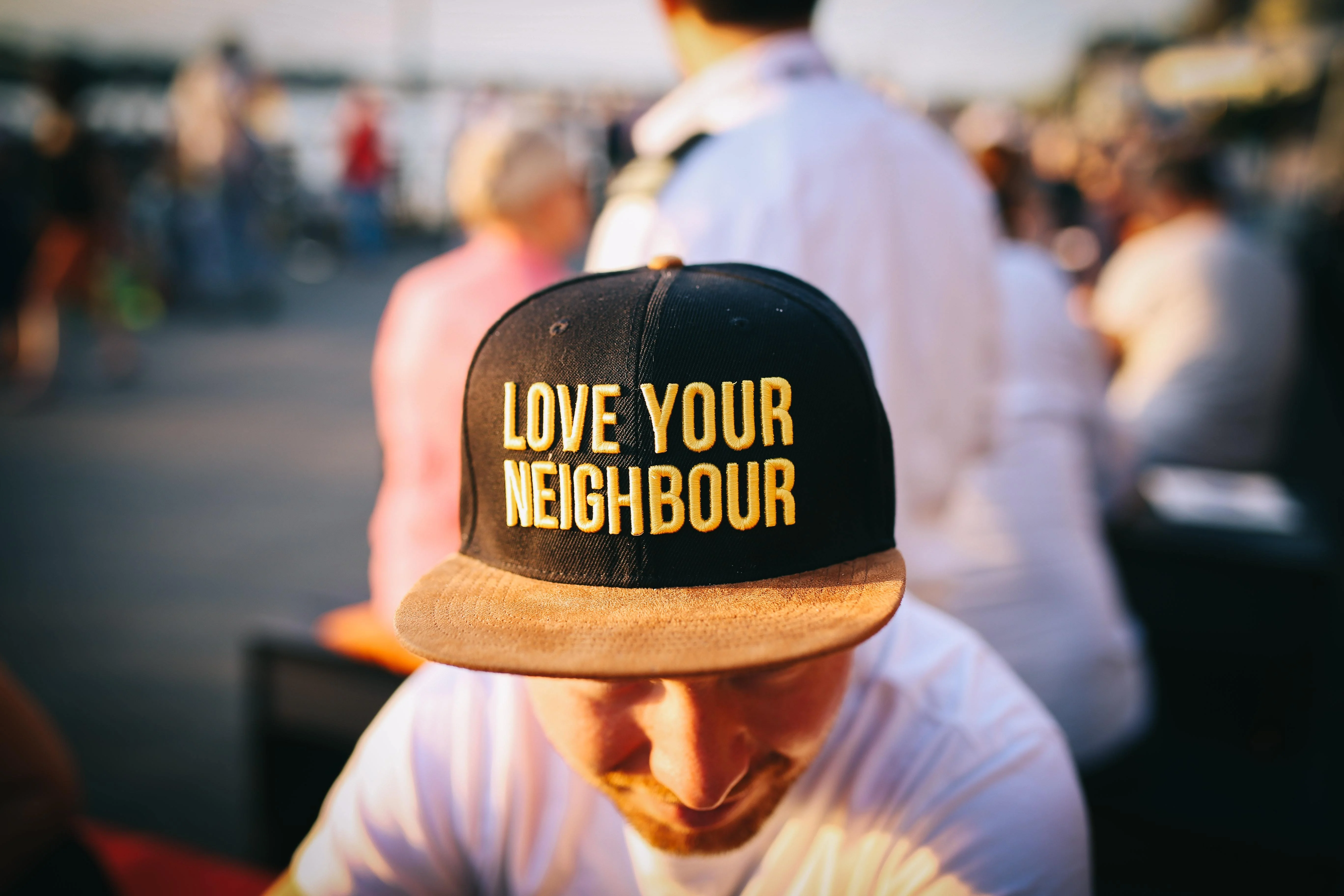 a man with his head down is wearing a hat that says 'love your neighbour' on it