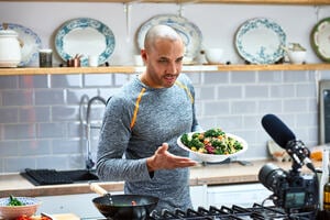 A man in a kitchen talking to camera with a plate of healthy food