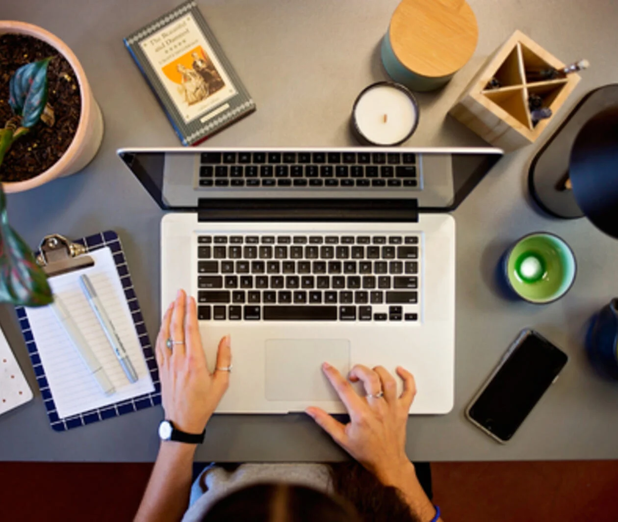 Overhead shot of person typing at a laptop with study materials surrounding.