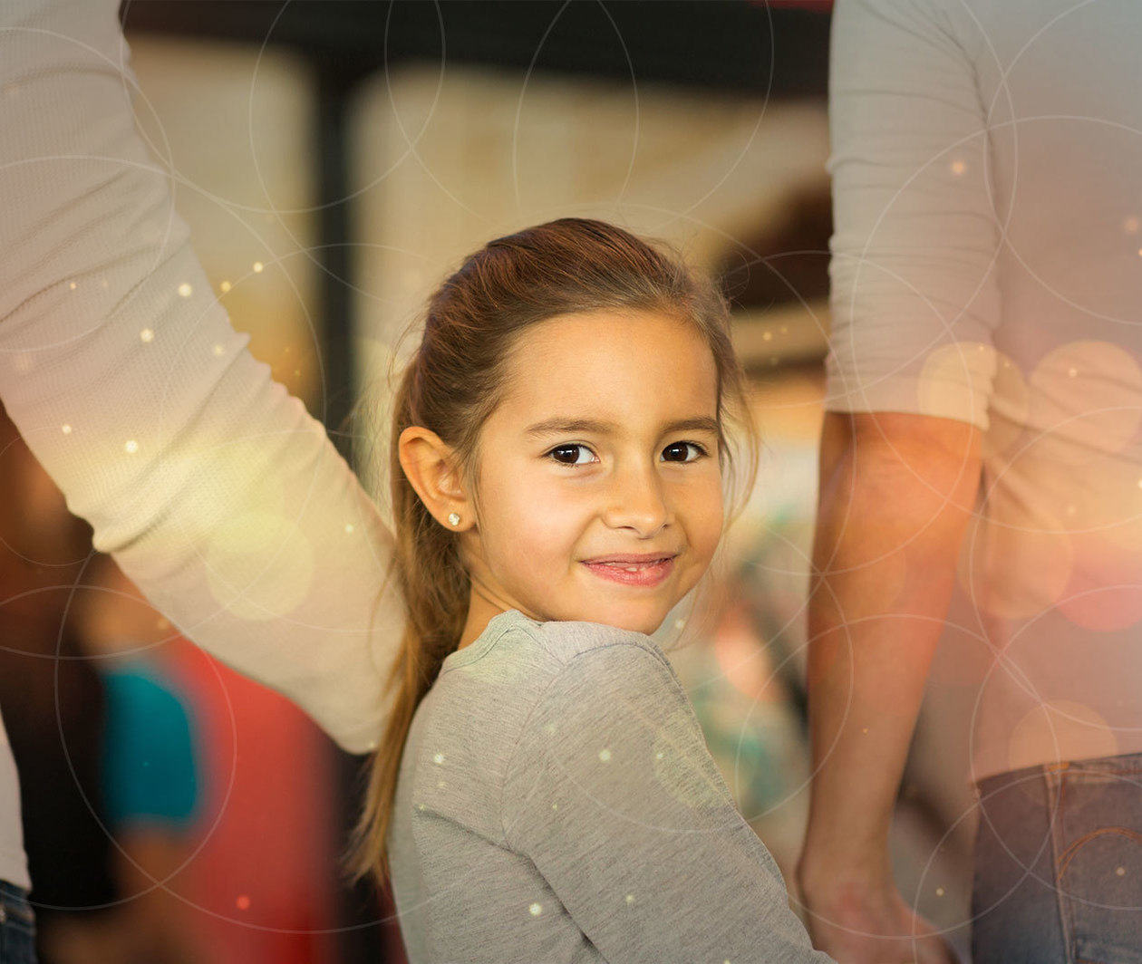 Smiling child holding hands with two protective adults