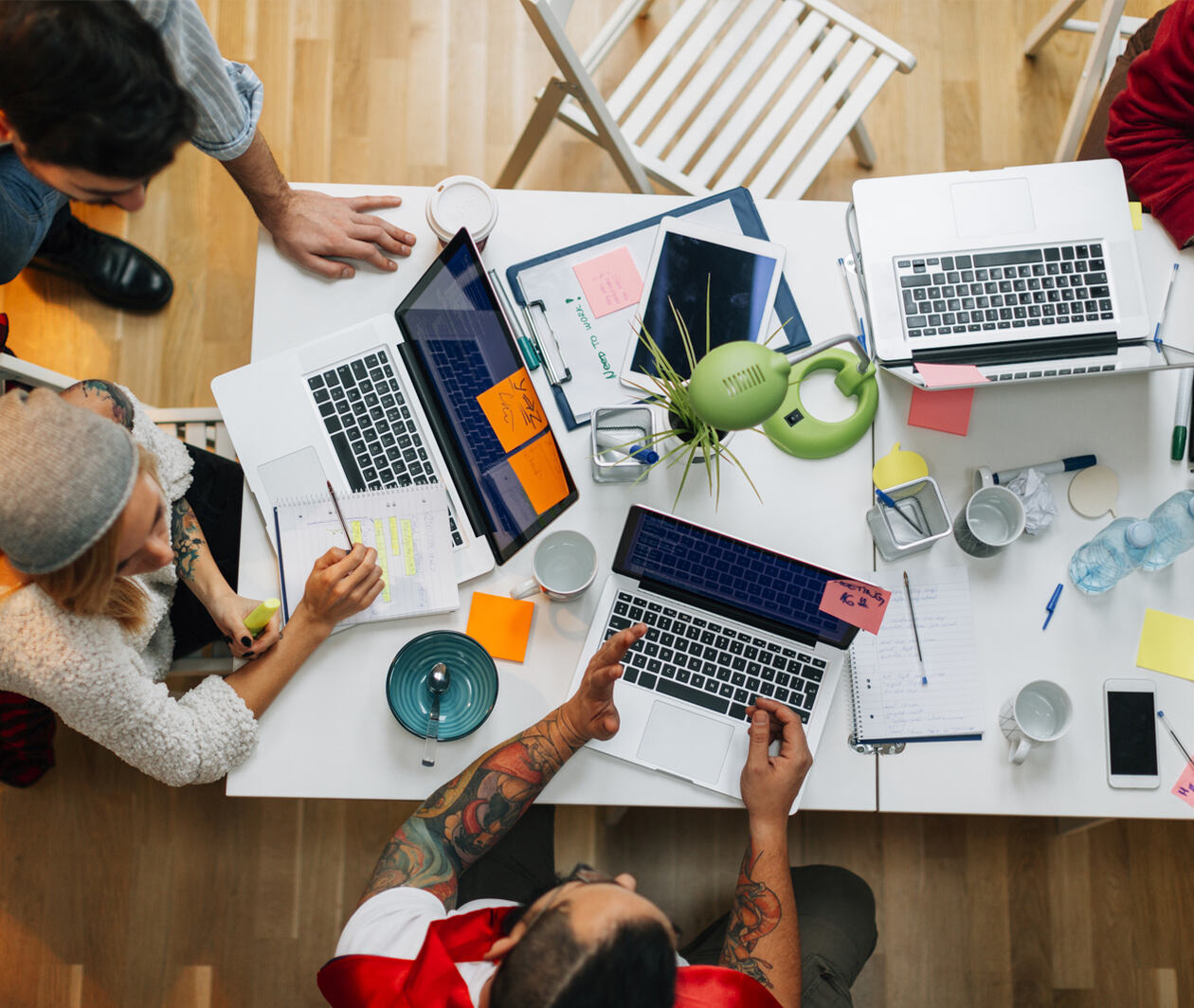 A photograph of several people working collaboratively on laptops.