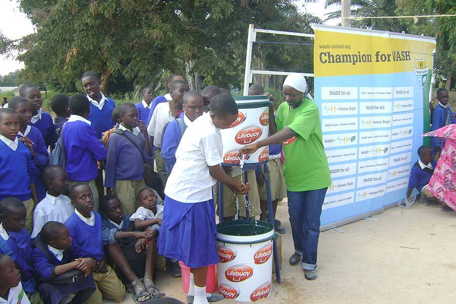 Group of schoolchildren watch a hand washing demonstration