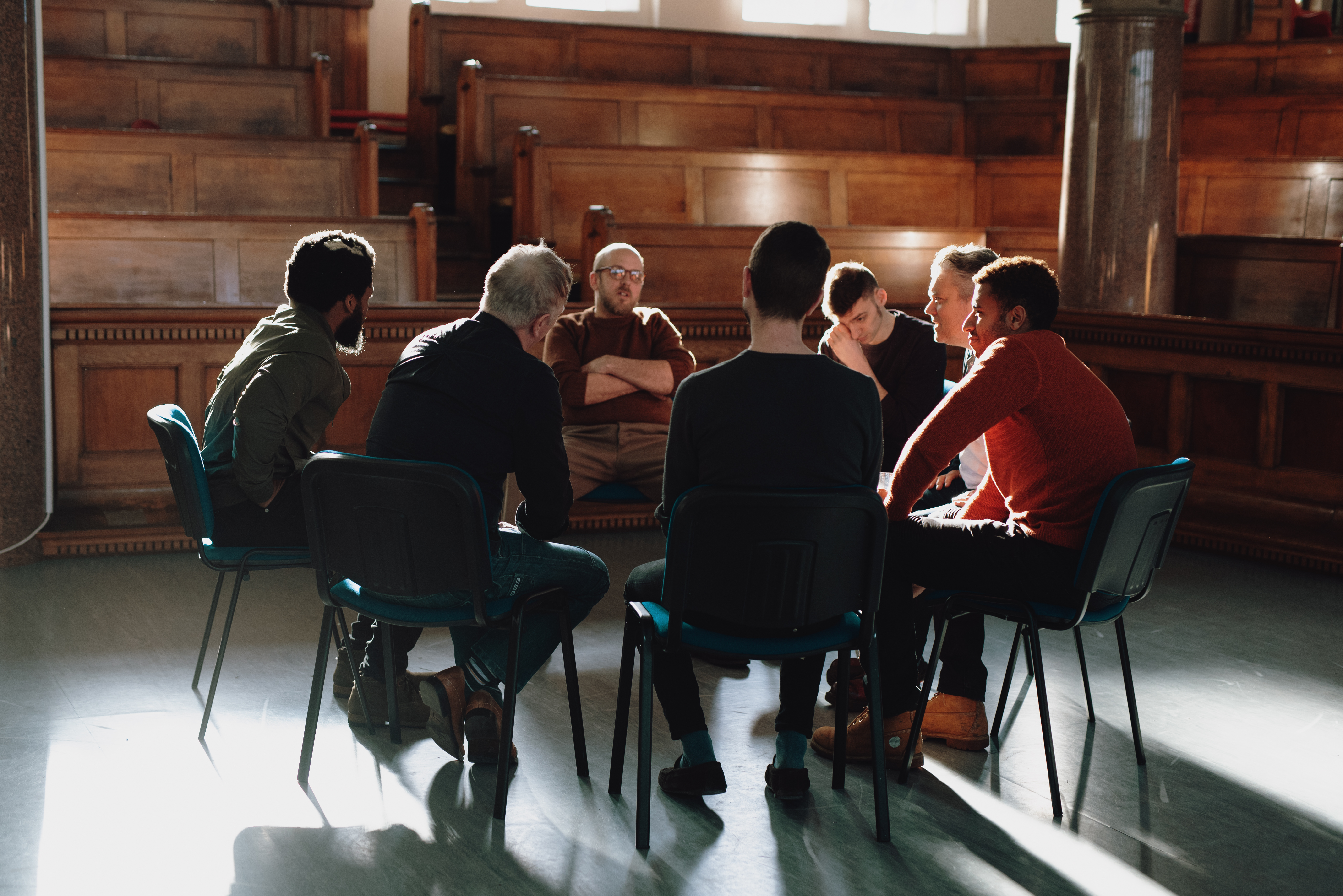 Group of men seated in a therapy session.