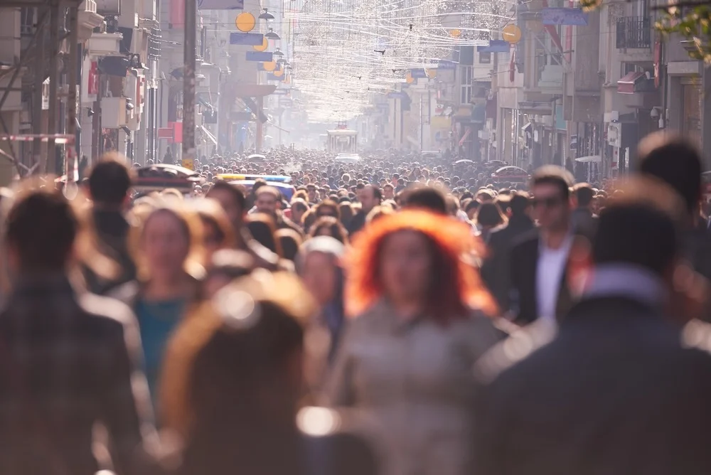 Long shot with hundreds of people walking down city arcade, middle ground in focus with blurred foreground and background.