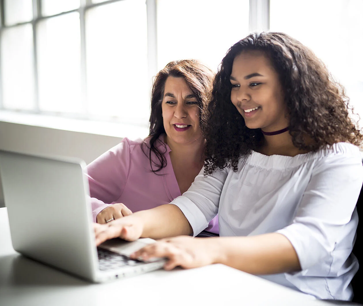 A young person with their parent or supporter are looking at a laptop screen 