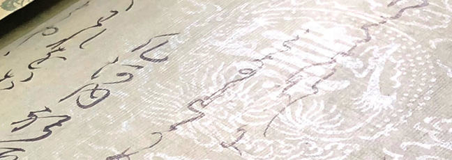 Verticaly written Japanese hand writing on a beautifully decorated white washi paper