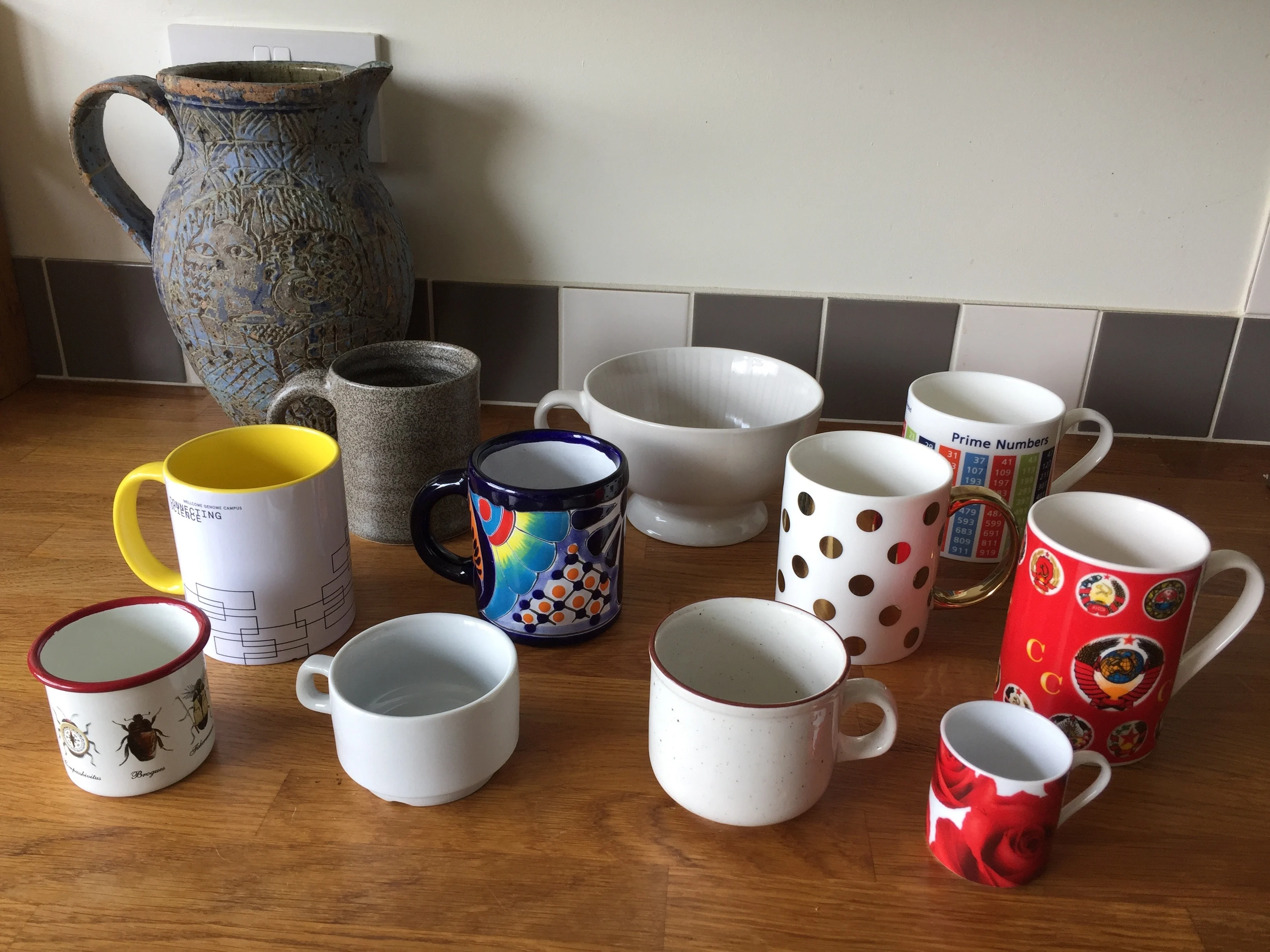 A variety of cups and mugs with one larger blue jug