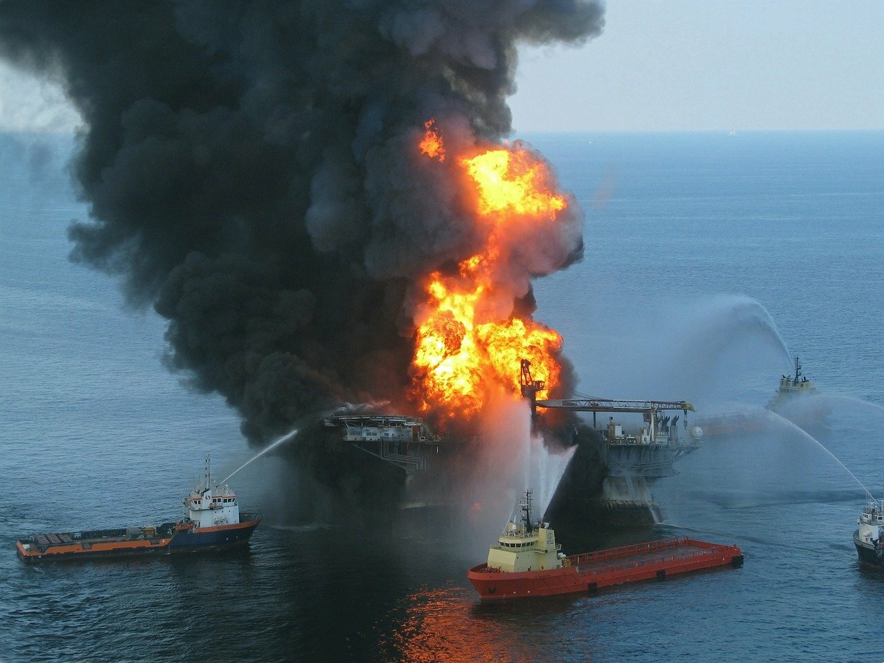 This image shows an oil rig in the middle of the ocean in flames.