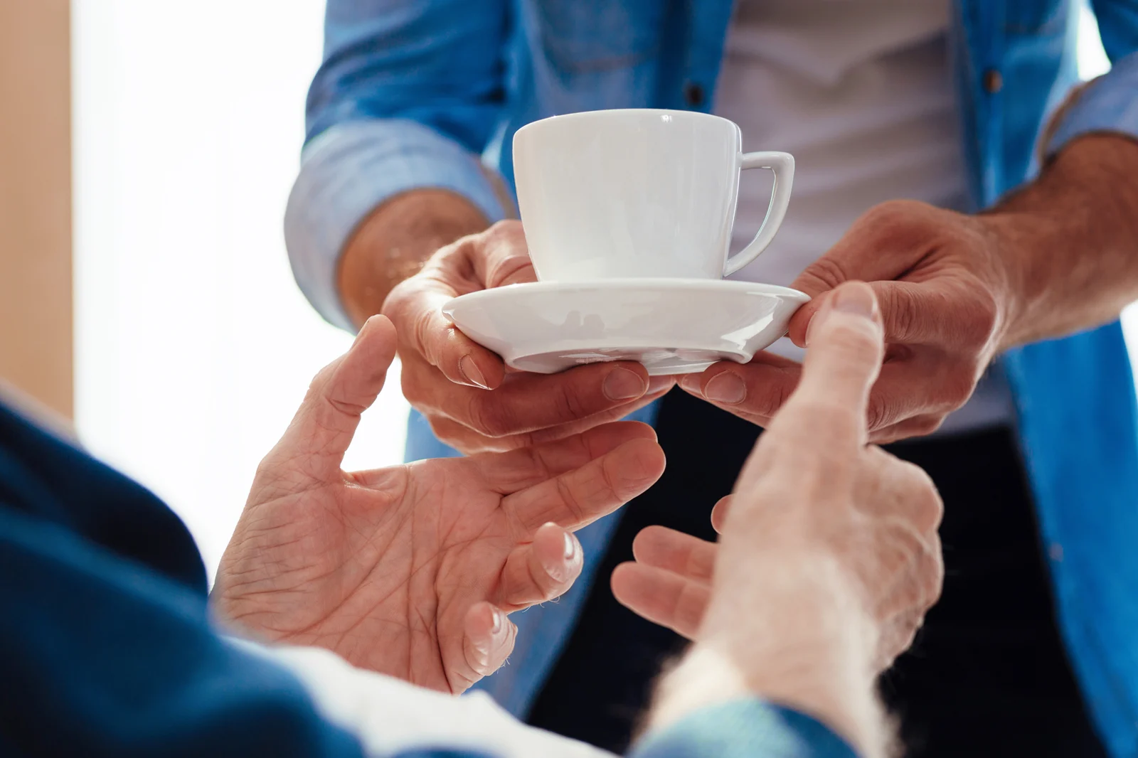 Close-up of a cup of tea being given to an elderly man