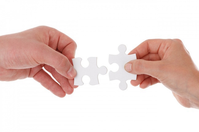 Two hands with two matching puzzle pieces