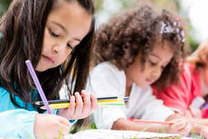 Inclusive education: a diverse group of children lie on grass completing school work