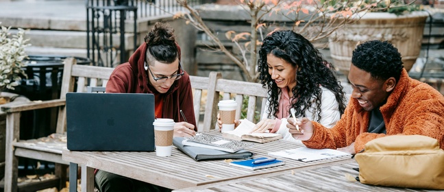 A group of young people sat drinking coffee with laptops. Image credit: Keira Burton, Pexels