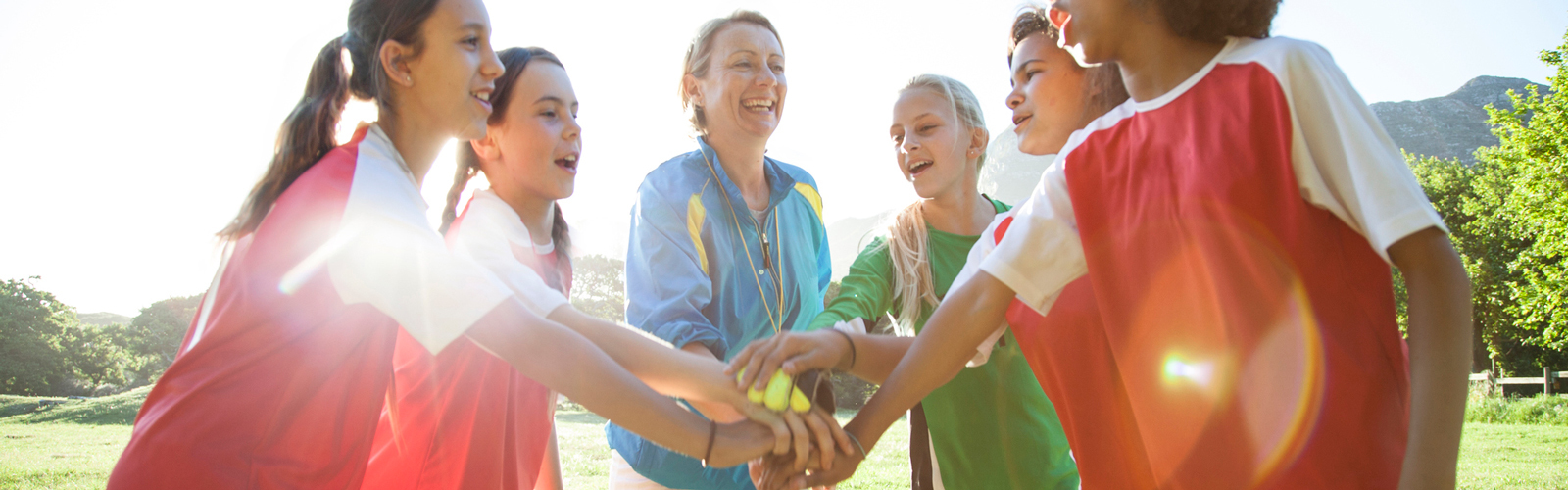 Girls' soccer team with their coach in a huddle